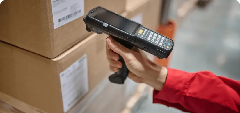 A worker using a handheld scanner to scan barcode on boxes.