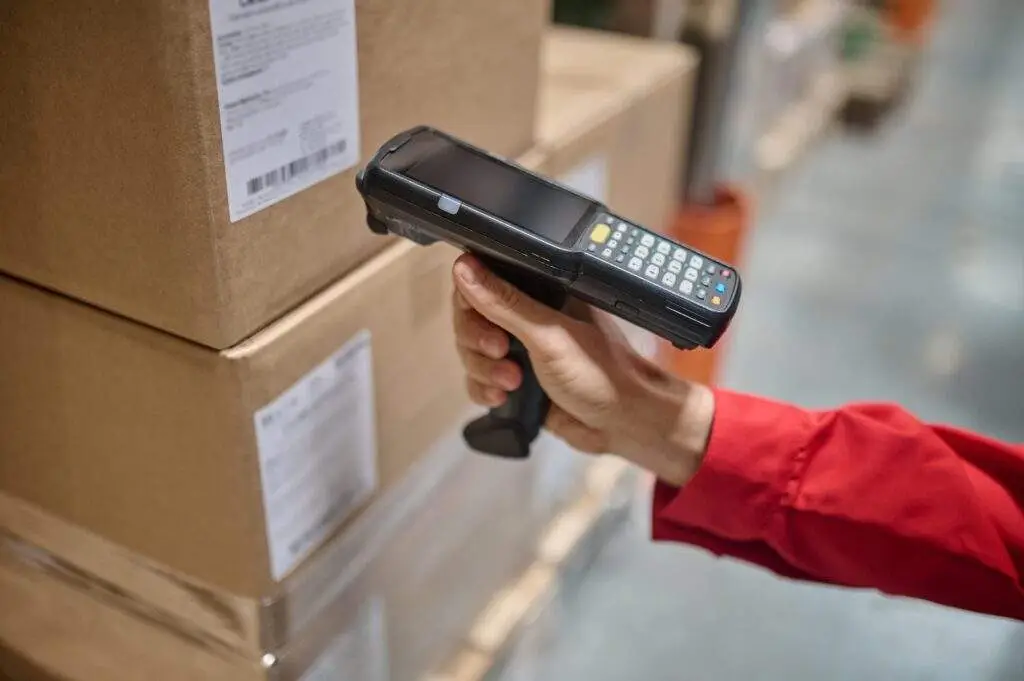 A worker using a handheld scanner to scan barcode on boxes.