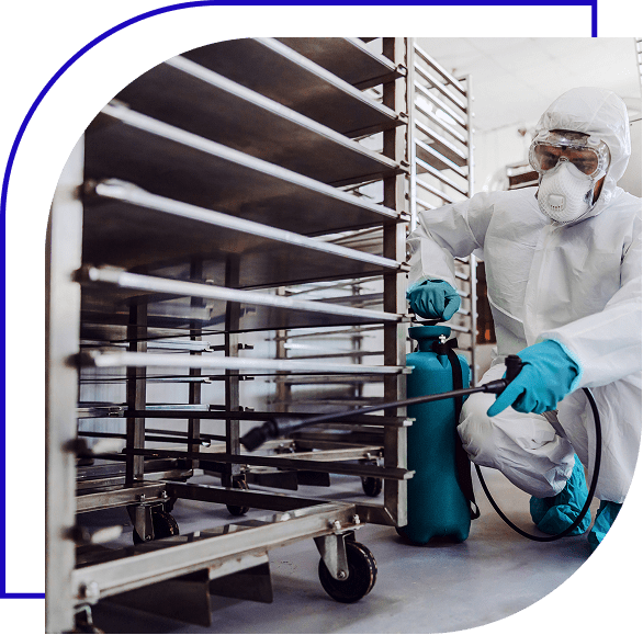 Sanitation worker spraying some cleaner on food equipment factory for cleaning.