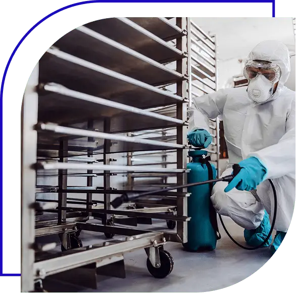 Sanitation worker spraying some cleaner on food equipment factory for cleaning.