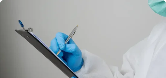 Laboratory person in full Protective lab outfit writing on clipboard with pen.