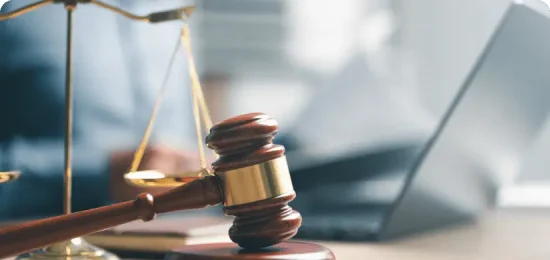 Gavel and laptop with blurred person background.