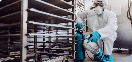 Sanitation worker spraying some cleaner on food equipment factory for cleaning.