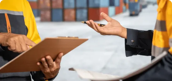 Two people discussing a shipment at a shipping container terminal.